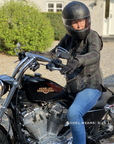 Person sitting on a Harley Davidson motorcycle wearing a helmet and plaid jacket.