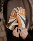 women's hands over a motorcycle gas tank while putting on colourful leather gloves from WILDUST