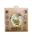 A square kraft paper packaging card with a circular cutout showing a floral fabric patch. The patch has a yellow rose on a cream background with the word 'Glow' in script.