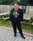 a smiling red haired woman wearing witches of wheels t-shirt, black jeans and mc jacket