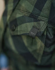 Close-up of a green plaid shirt with a tag on a blurred background
