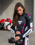 Young woman wearing black, white, pink SHIMA motorcycle  leather suit with her red motorcycle