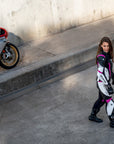 Young woman wearing black, white, pink SHIMA motorcycle  leather suit with her red motorcycle
