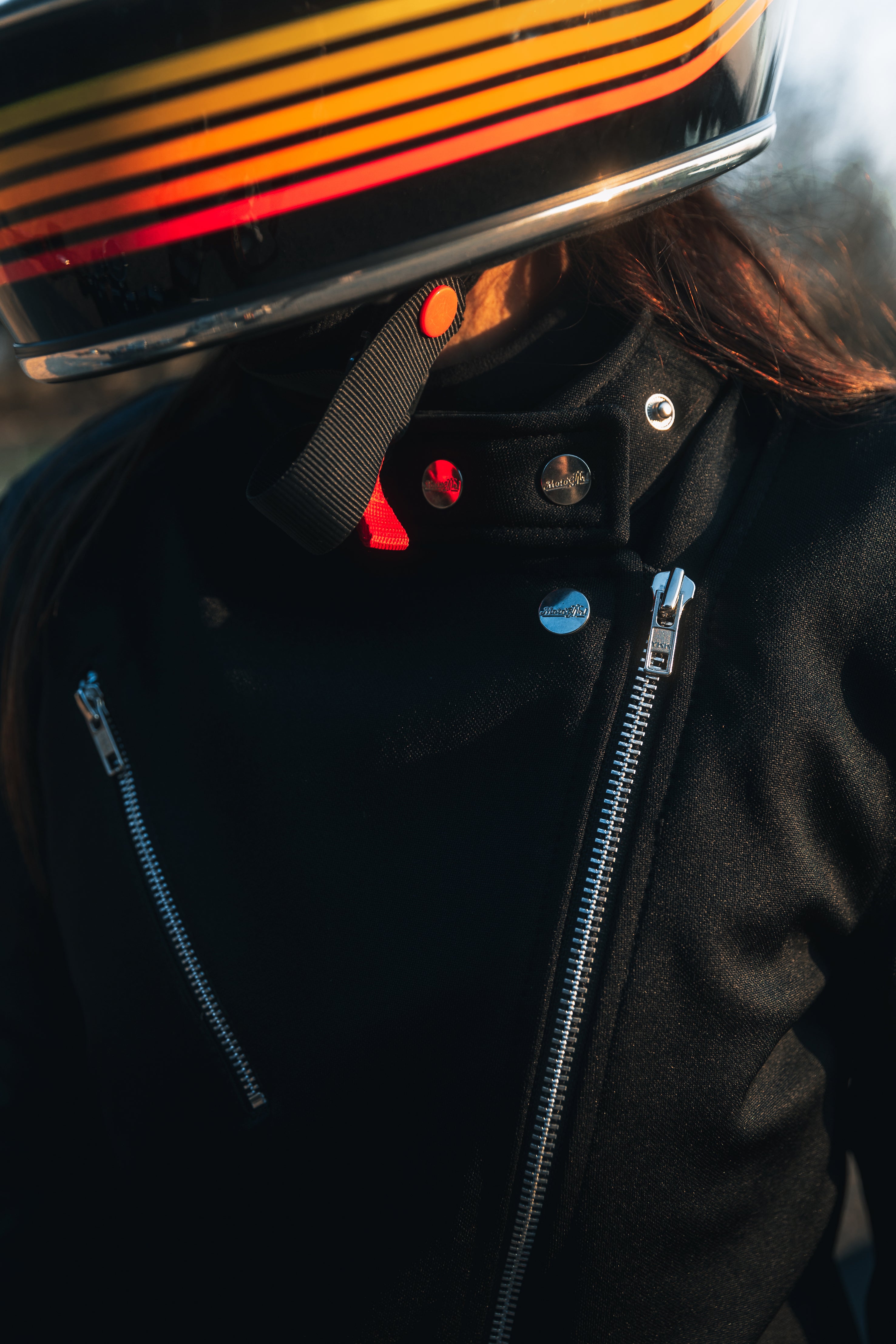 woman with a helmet wearing Black retro style woman's motorcycle jacket with silver zip details