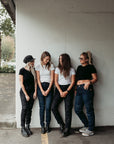 Four smiling women wearing black and blue women’s motorcycle jeans from Moto Girl.