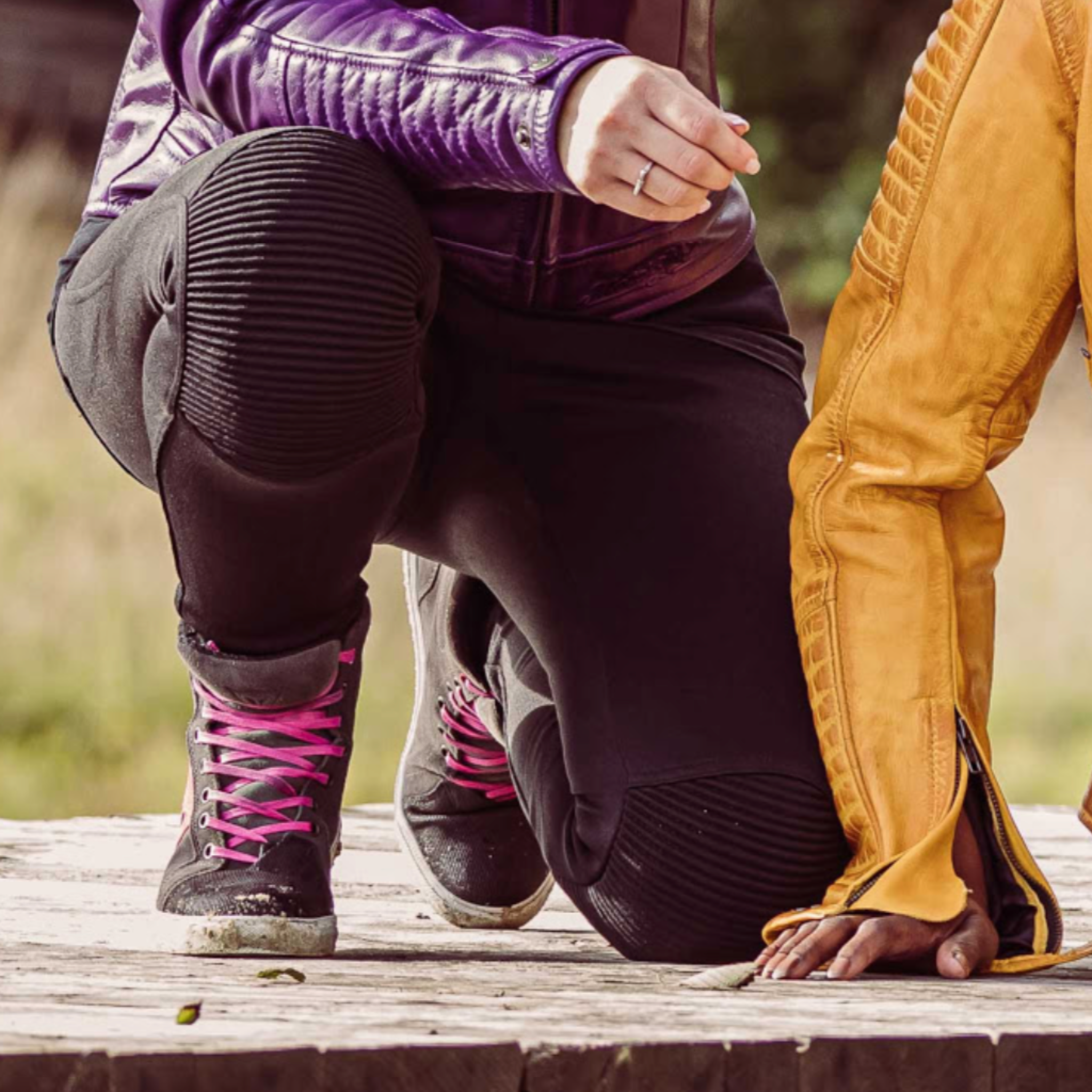 Close up of a woman's knee with black motorcycle leggings sherrie and Valerie purple jacket