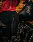 Close up of a woman's, sitting on the motorcycle and wearing black motorcycle leggings,  knee