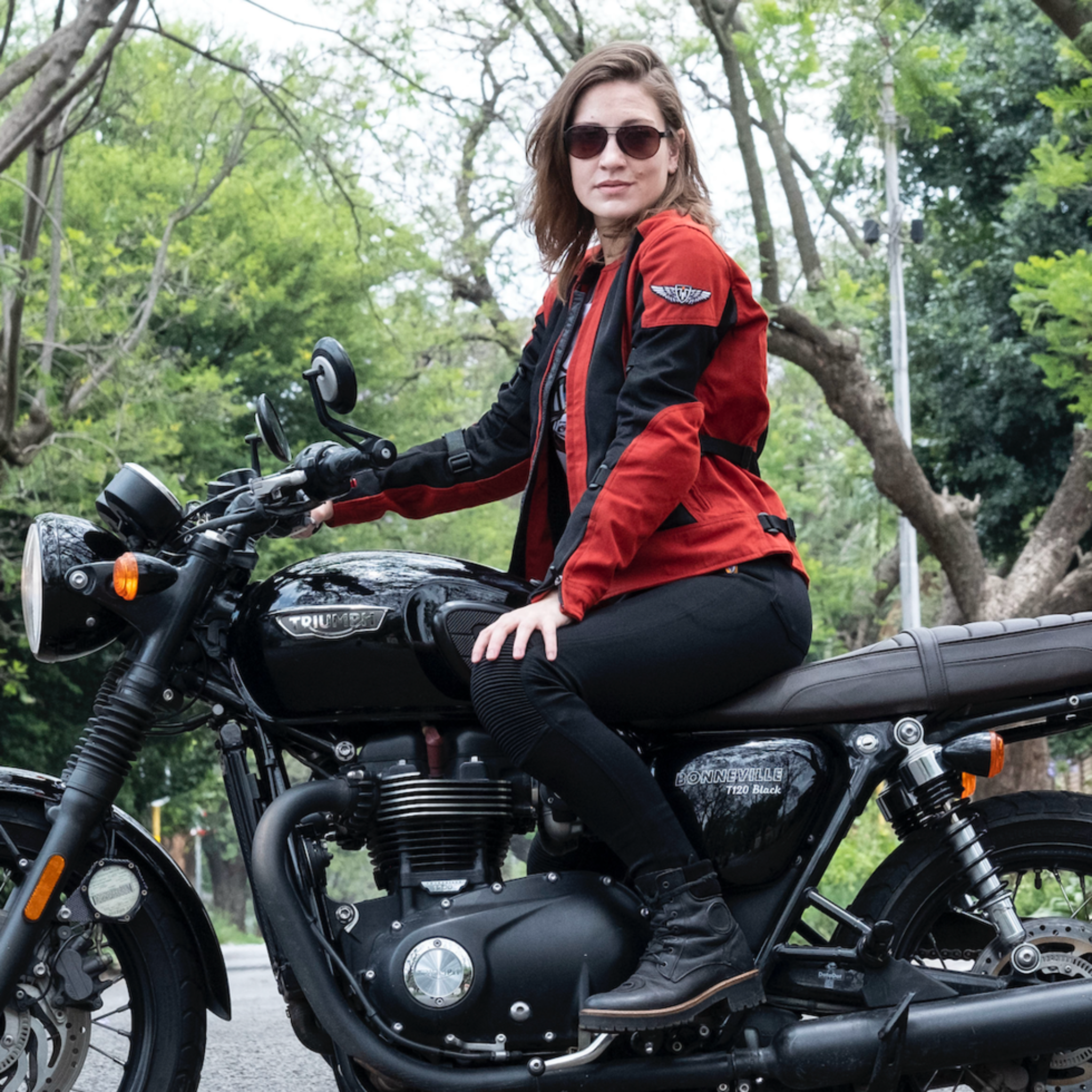 a young woman on a Triumph motorcycle wearing red and black women's motorcycle summer jacket from Moto Girl