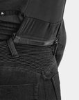 Close-up of a black tactical backpack with multiple zippers and straps on a light gray background.