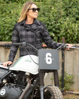 woman with sunglasses next to a motocross bike wearing a black & grey flannel style women's jacket 