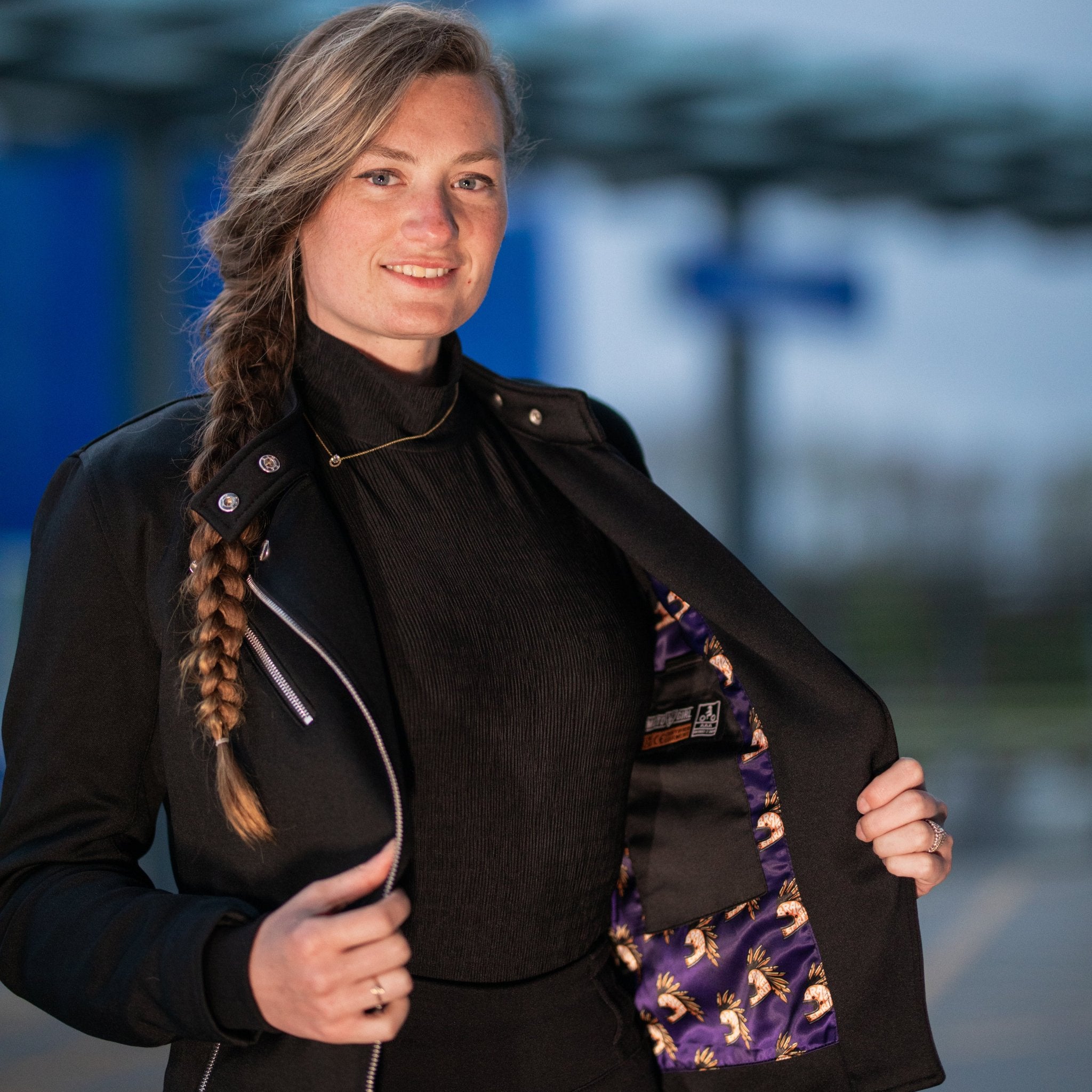 a young woman opening her Black retro style woman's motorcycle jacket with silver zip details