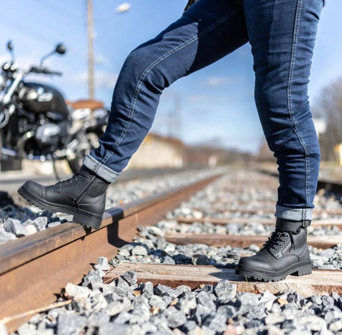 Woman&#39;s legs standing on the railway and wearing black motorcycle boots