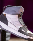 Gray and black high-top sneakers with white soles on a purple background