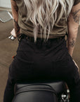 a back of a woman siting on a motorcycle wearing adjustable waist black mc pants 
