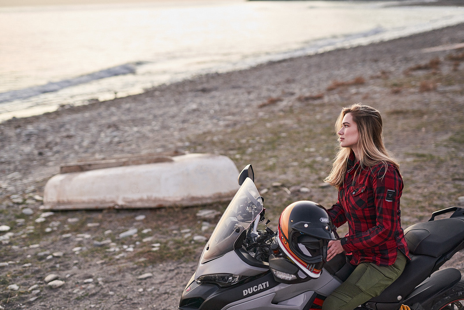 Woman sitting on a Ducati scooter by a beach