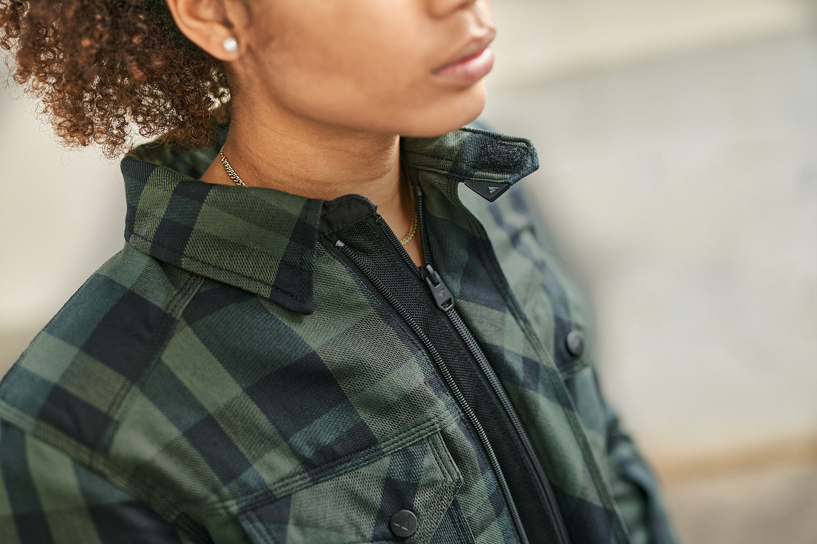 Person wearing a green plaid jacket with a blurred background