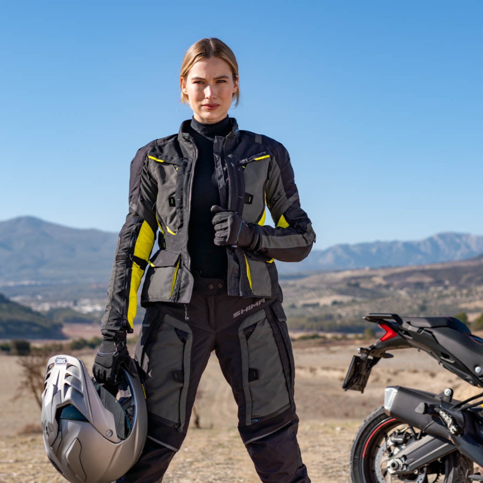 a. woman standing by her motorcycle wearing black fluo motorcycle lady jacket