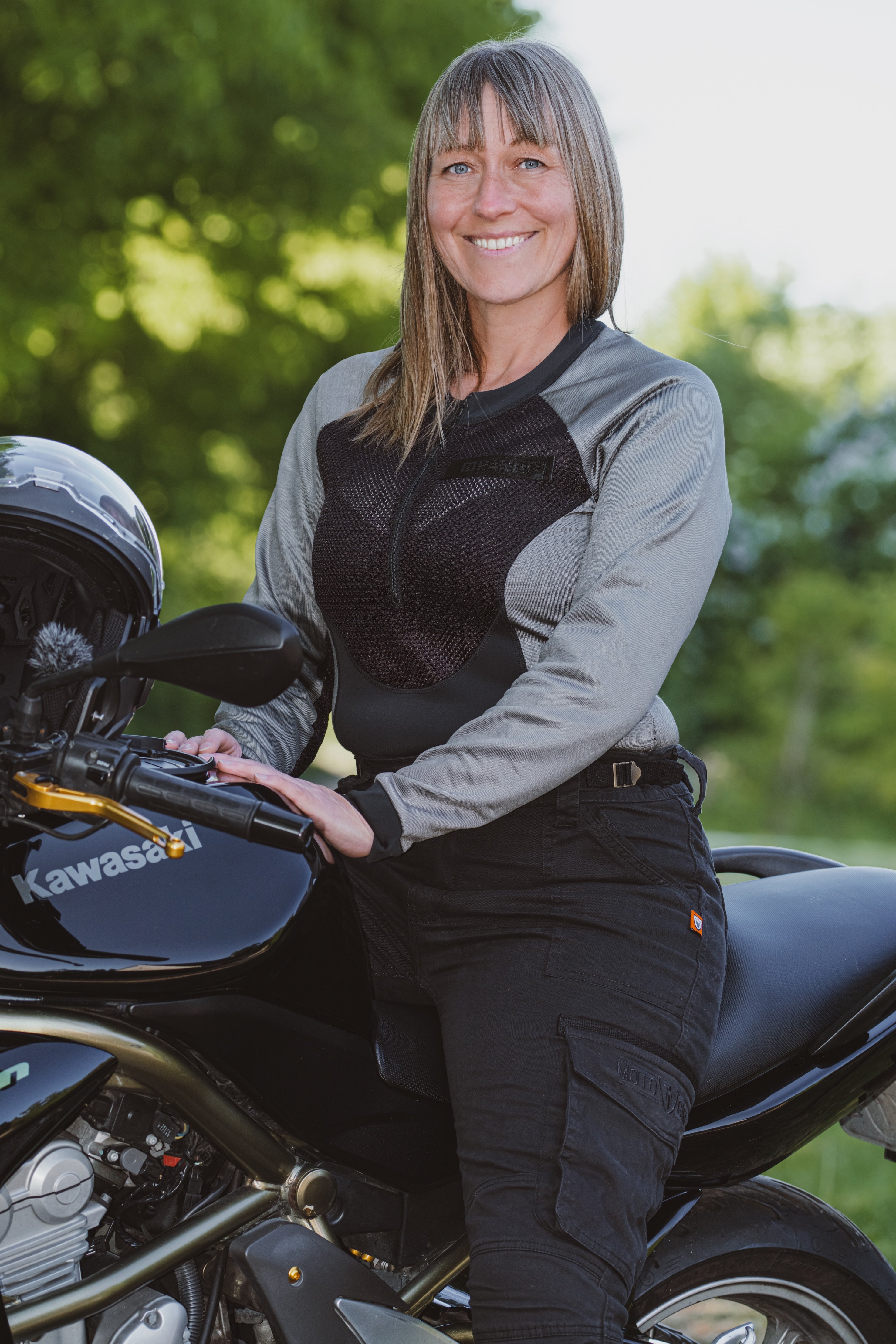 Woman standing next to a Kawasaki motorcycle with a blurred green background