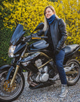 A blond woman on a motorcycle wearing black leather jacket 