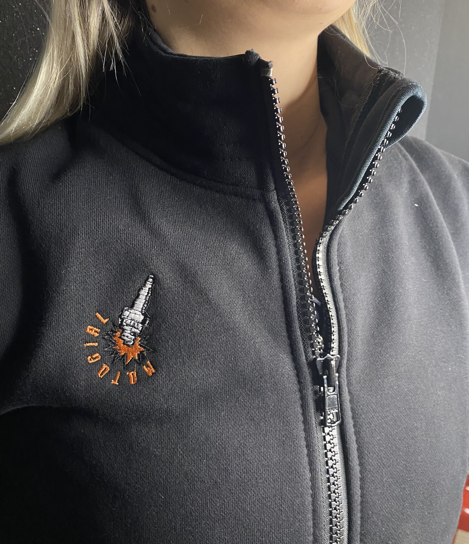 a close up of a woman&#39;s neck wearing black sweatshirt with a zip and MotoGirl embroidery 