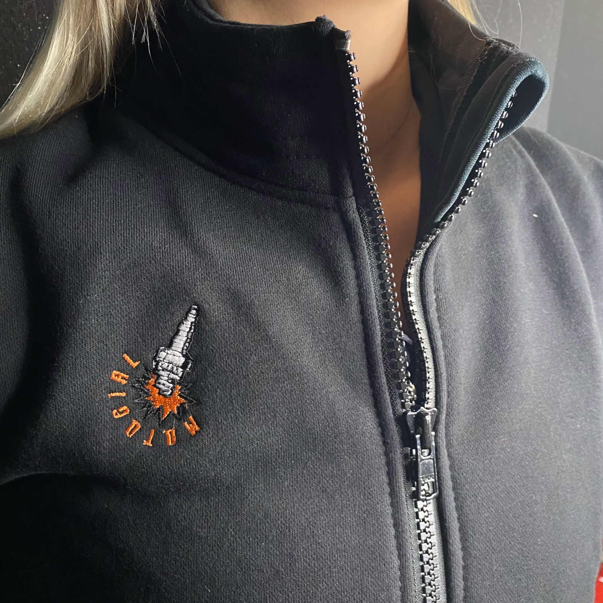 a close up of a woman&#39;s neck wearing black sweatshirt with a zip and MotoGirl embroidery 