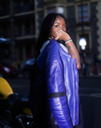 a black woman holding her purple motorcycle leather jacket on the shoulder