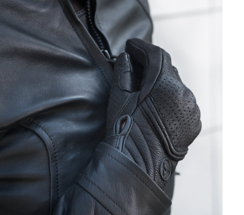 Women closing motorcycle jacket&#39;s zipper wearing black leather Shima motorcycle gloves