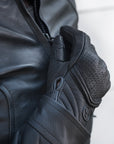 Women closing motorcycle jacket's zipper wearing black leather Shima motorcycle gloves