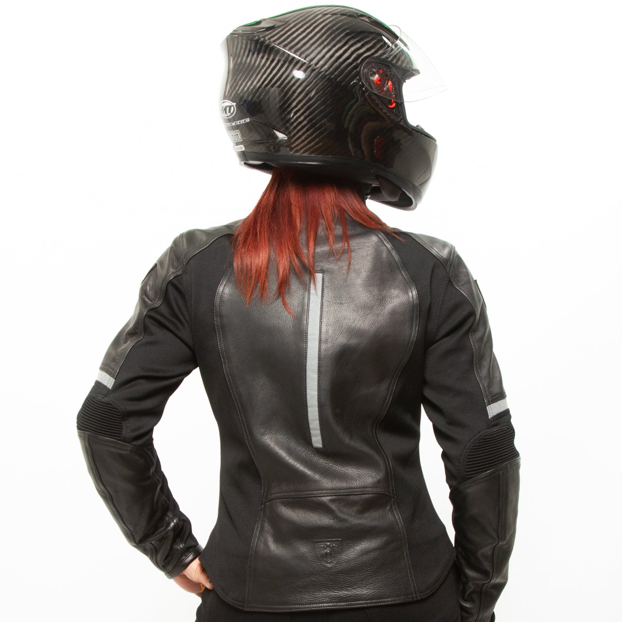 A red-haired woman wearing a helmet posing in a black leather women&#39;s motorcycle jacket with reflectors from Moto Girl