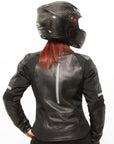 A red-haired woman wearing a helmet posing in a black leather women's motorcycle jacket with reflectors from Moto Girl