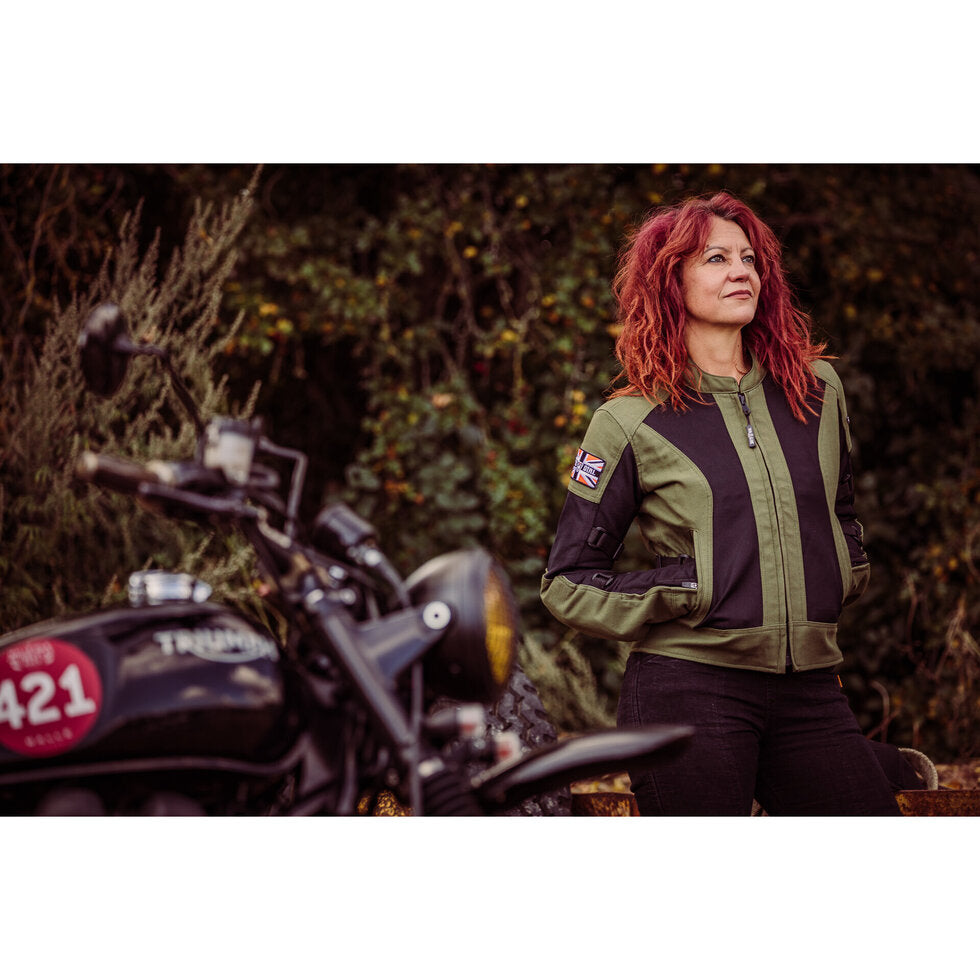 A women standing in front of a motorcycle wearing Women&#39;s motorcycle summer mesh jacket in black and green from Moto Girl