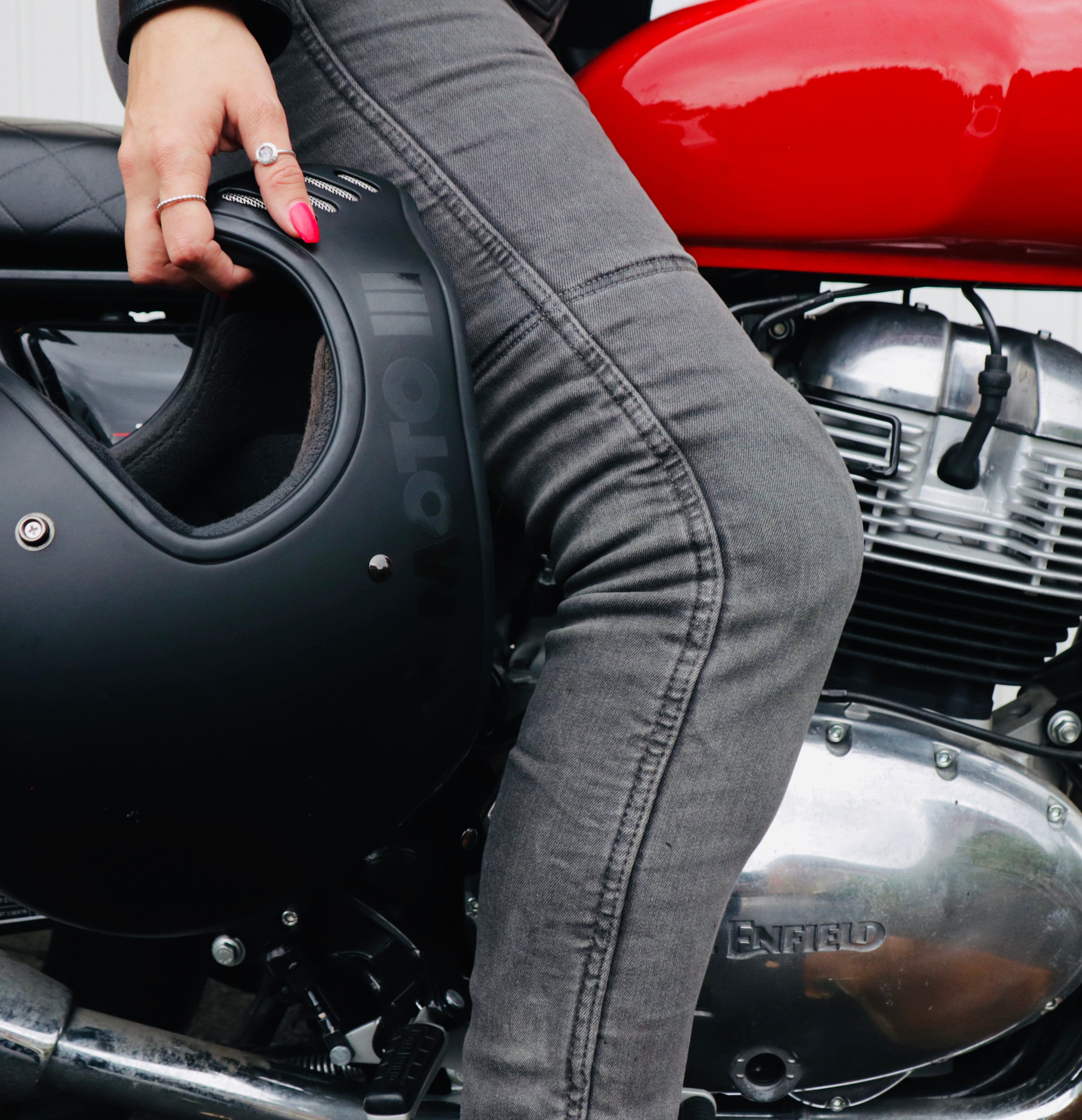 Woman's, sitting on a motorcycle, leg wearing grey MotoGirl Melissa motorcycle Jeggings and holding a helmet