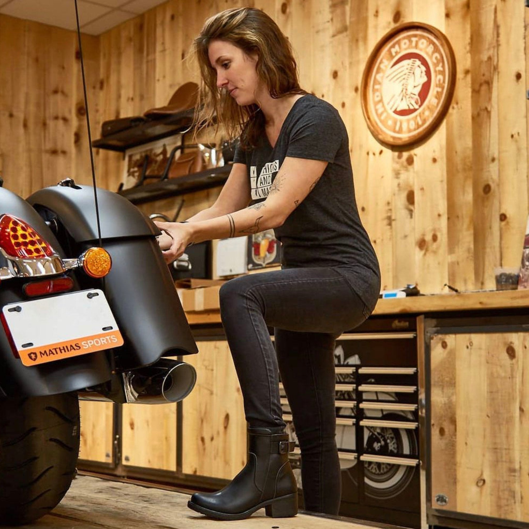 Woman mechanic in the garage wearing women's black leather motorcycle shoes 