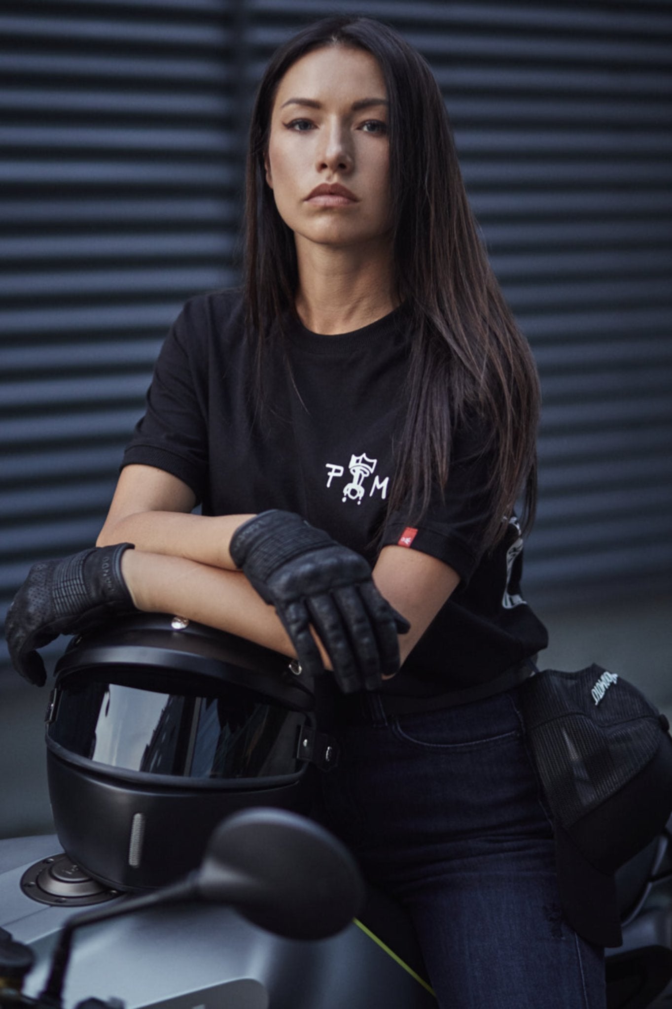 A young woman on a motorcycle leaning on a helmet