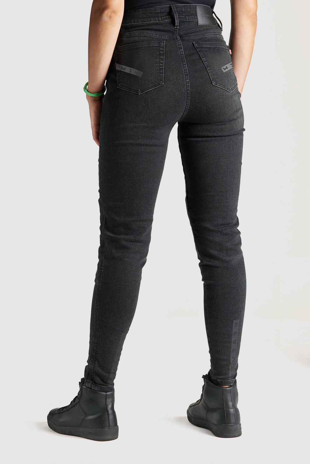 woman&#39;s legs  from the back wearing black high waist motorcycle jeans