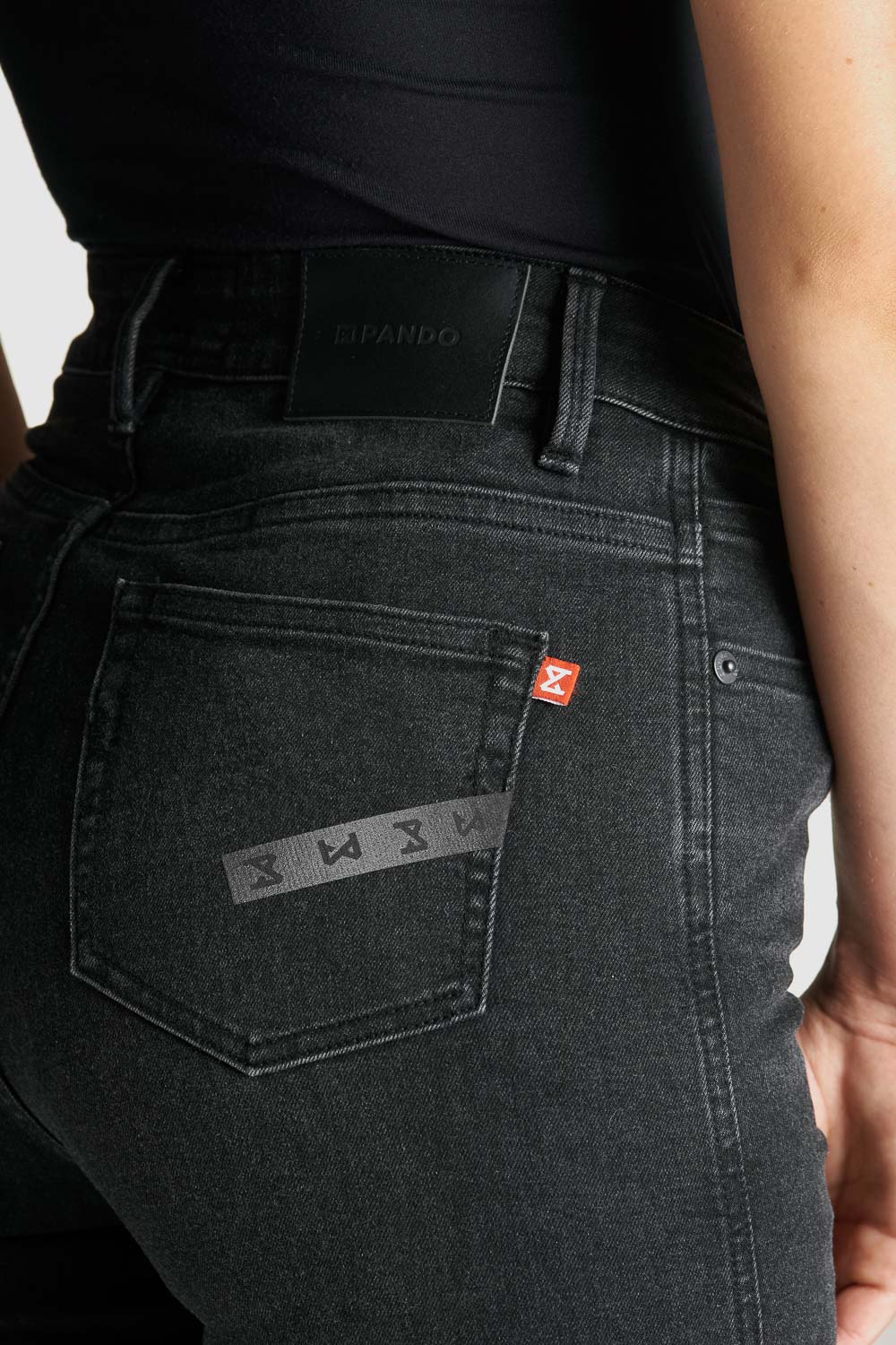 A close up of a woman&#39;s waist wearing black high waist motorcycle jeans