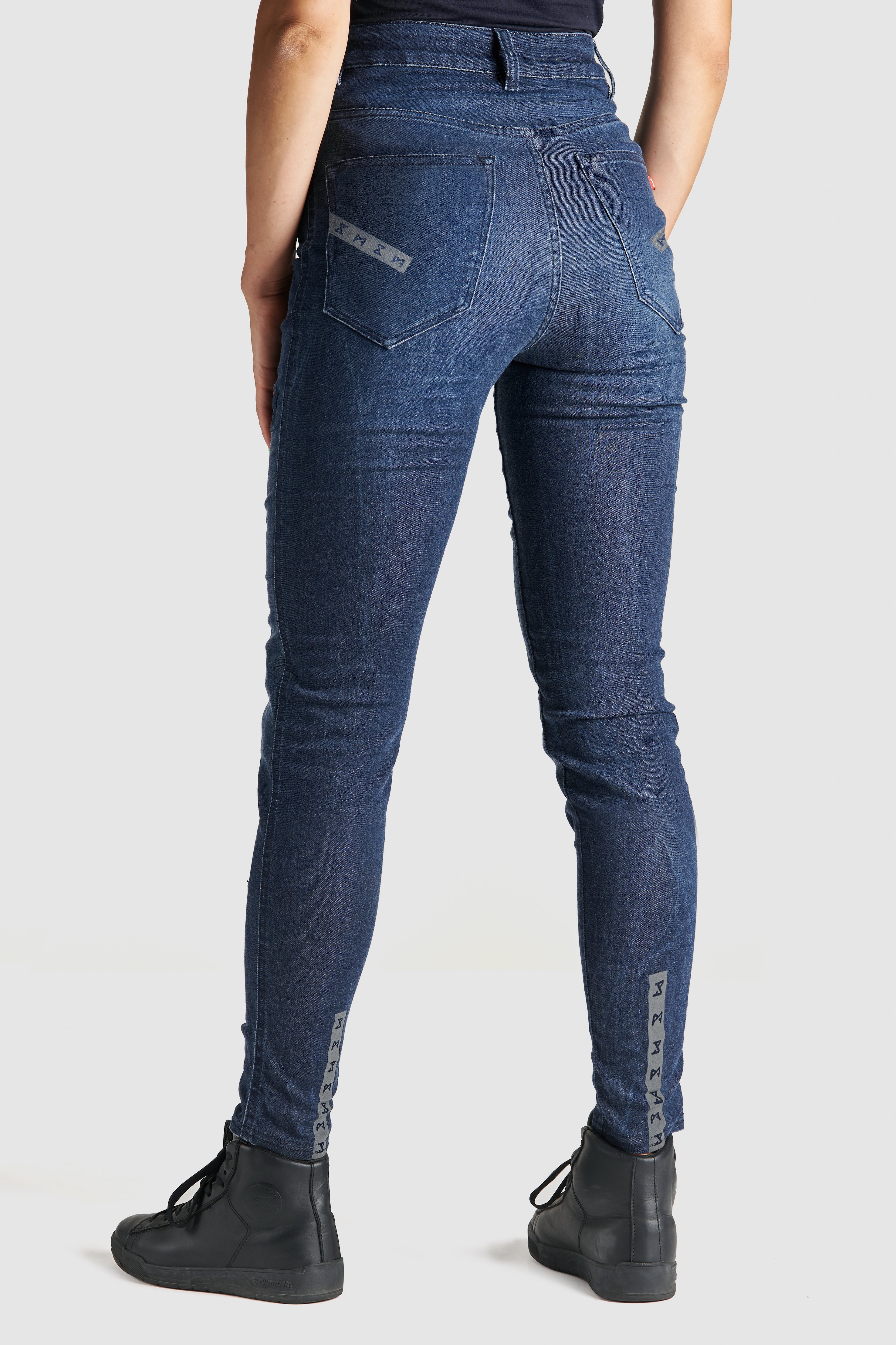 Woman&#39;s legs from the back wearing blue motorcycle jeans 