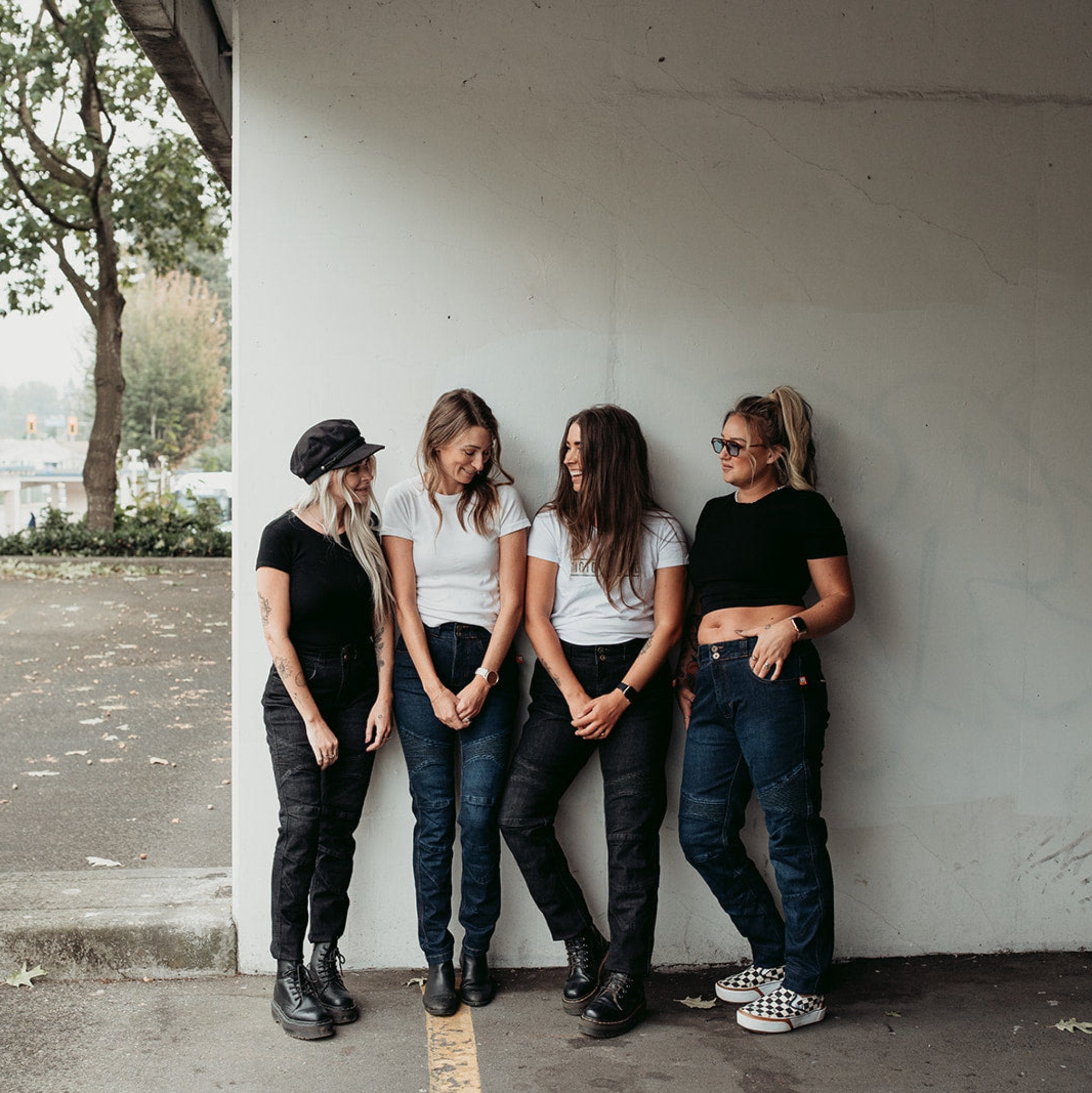 Four smiling women wearing black and blue women’s motorcycle jeans from Moto Girl.