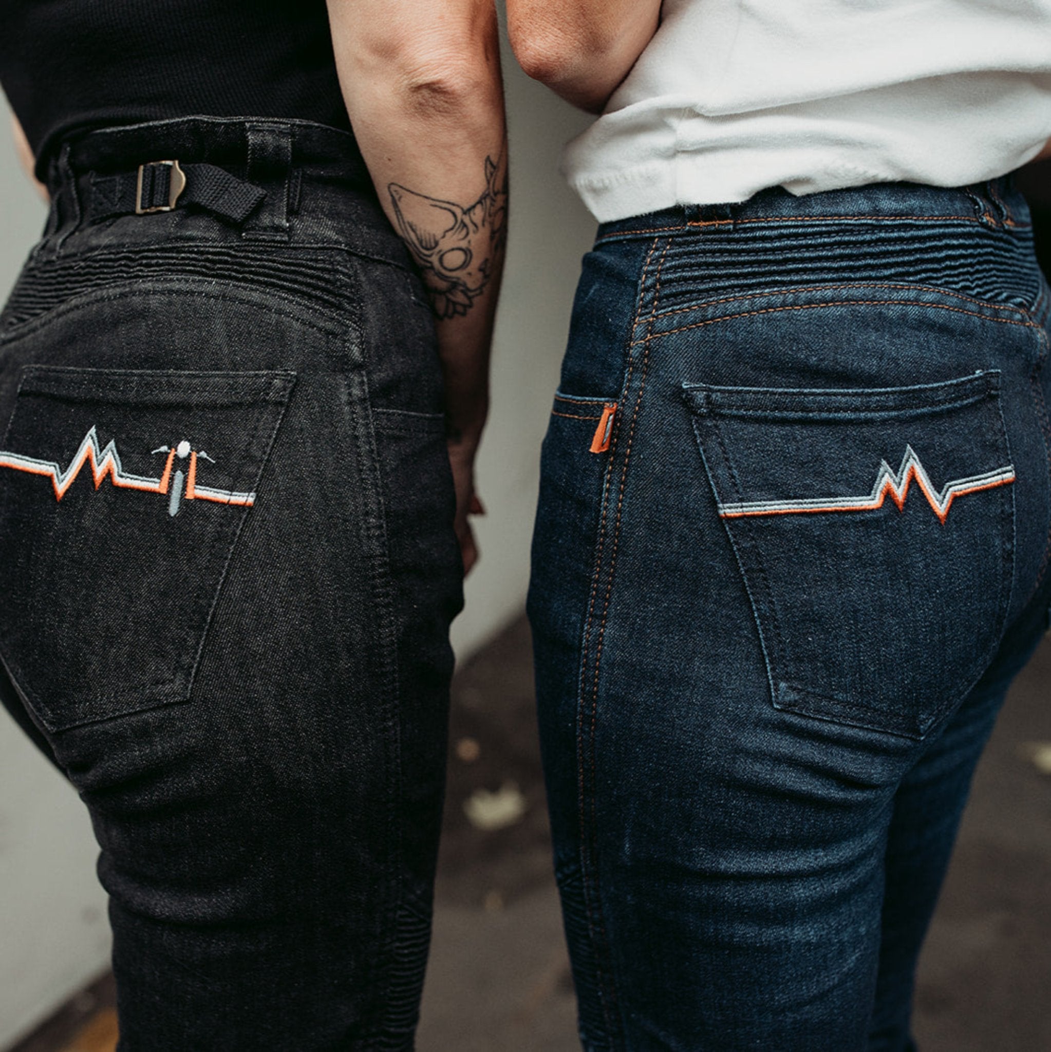 The backs of two women wearing women&#39;s motorcycle jeans from Moto Girl with heartbeat detail.