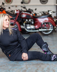 A blong woman sitting on the floor by motorcycles wearing women's motorcycle jacket from Moto Girl 