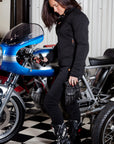 A woman standing by a motorcycle wearing women's motorcycle clothes from MotoGirl 