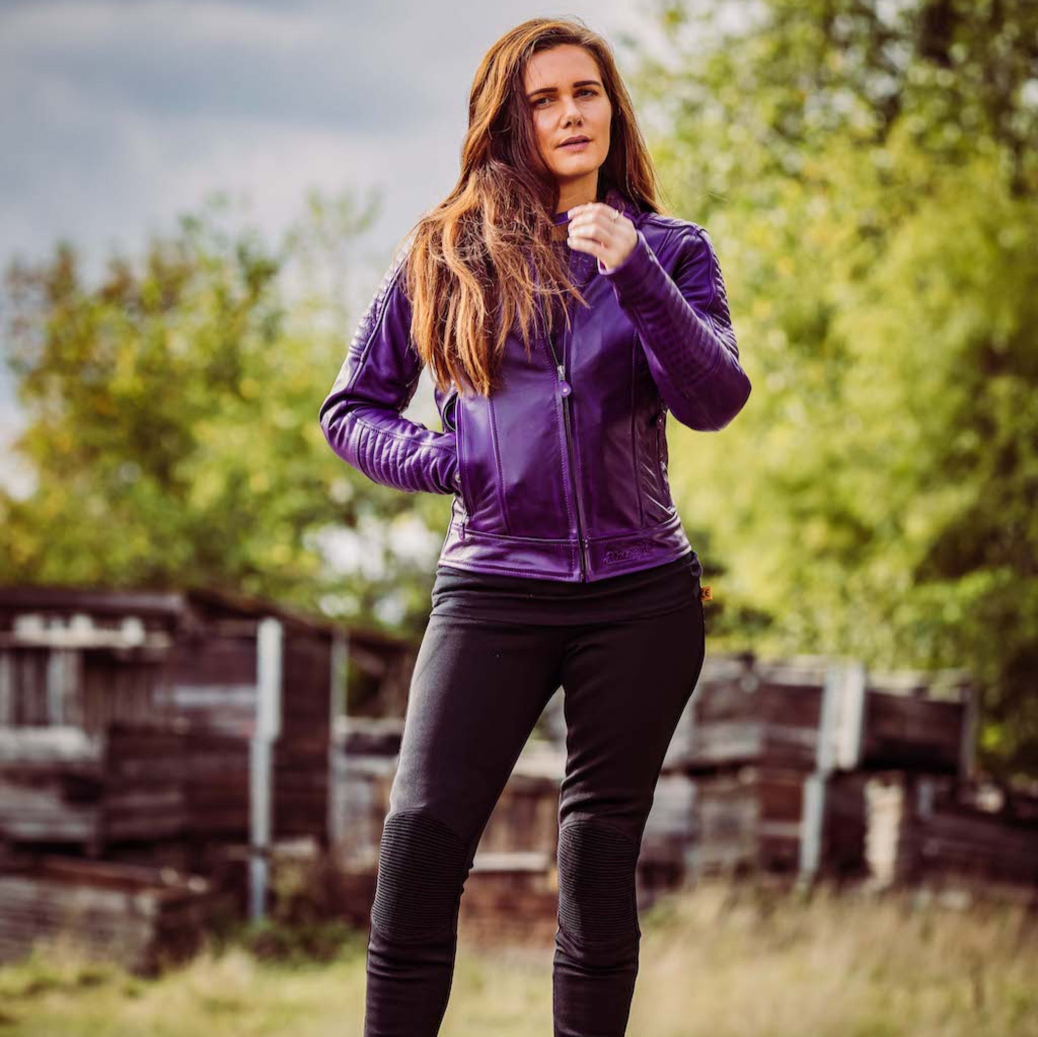 woman standing outside wearing a purple Valerie leather jacket and mc trousers 