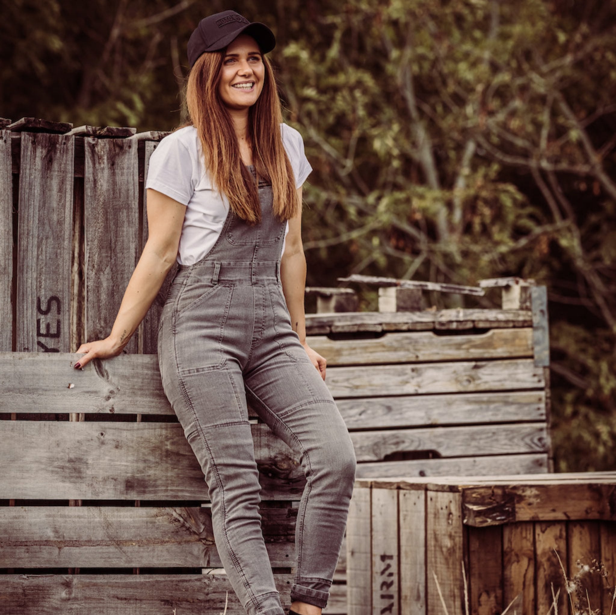 A woman wearing white tshirt and grey motorcycle overall 