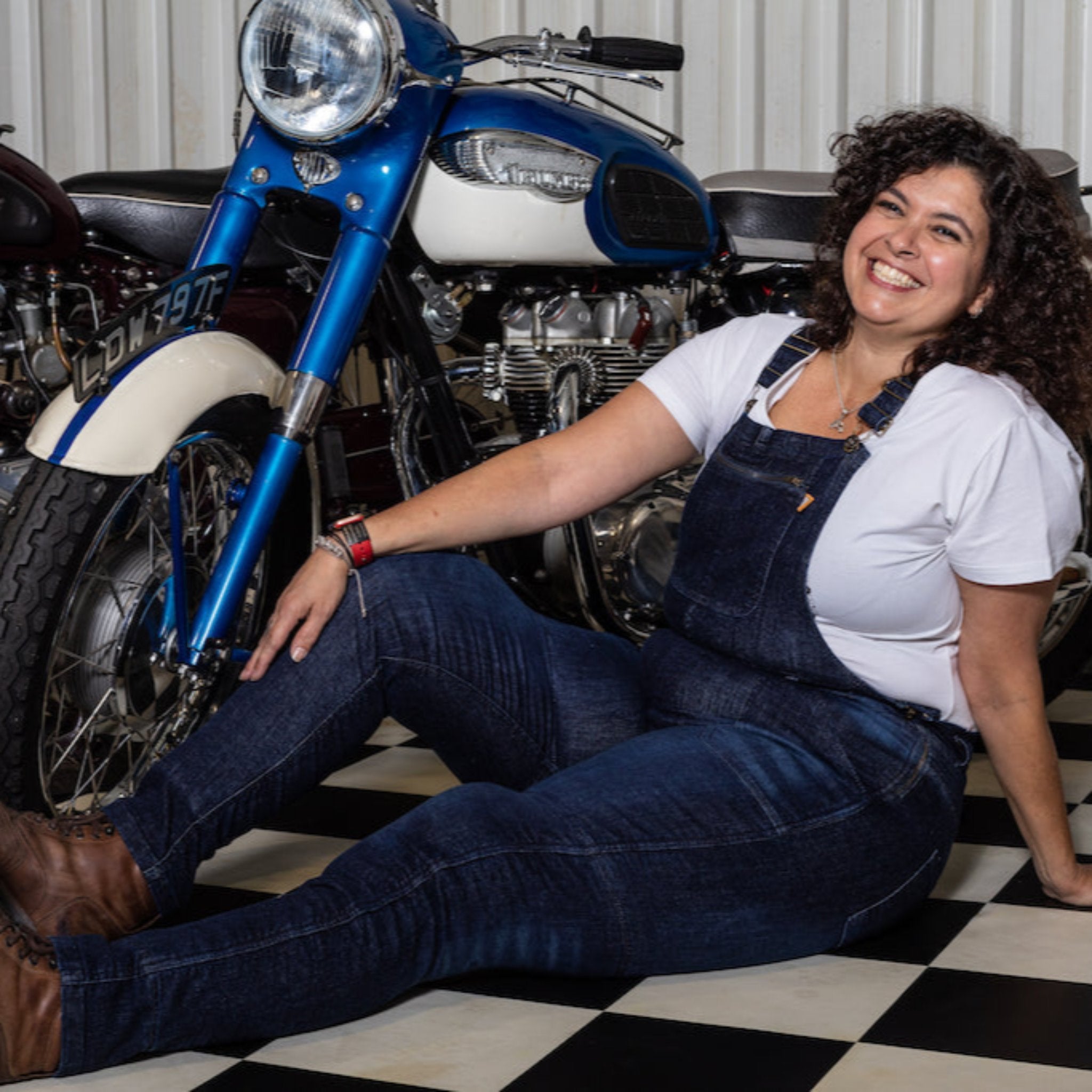 A woman siting by the motorcycle wearing Blue kevlar motorcycle overall for women from Motogirl