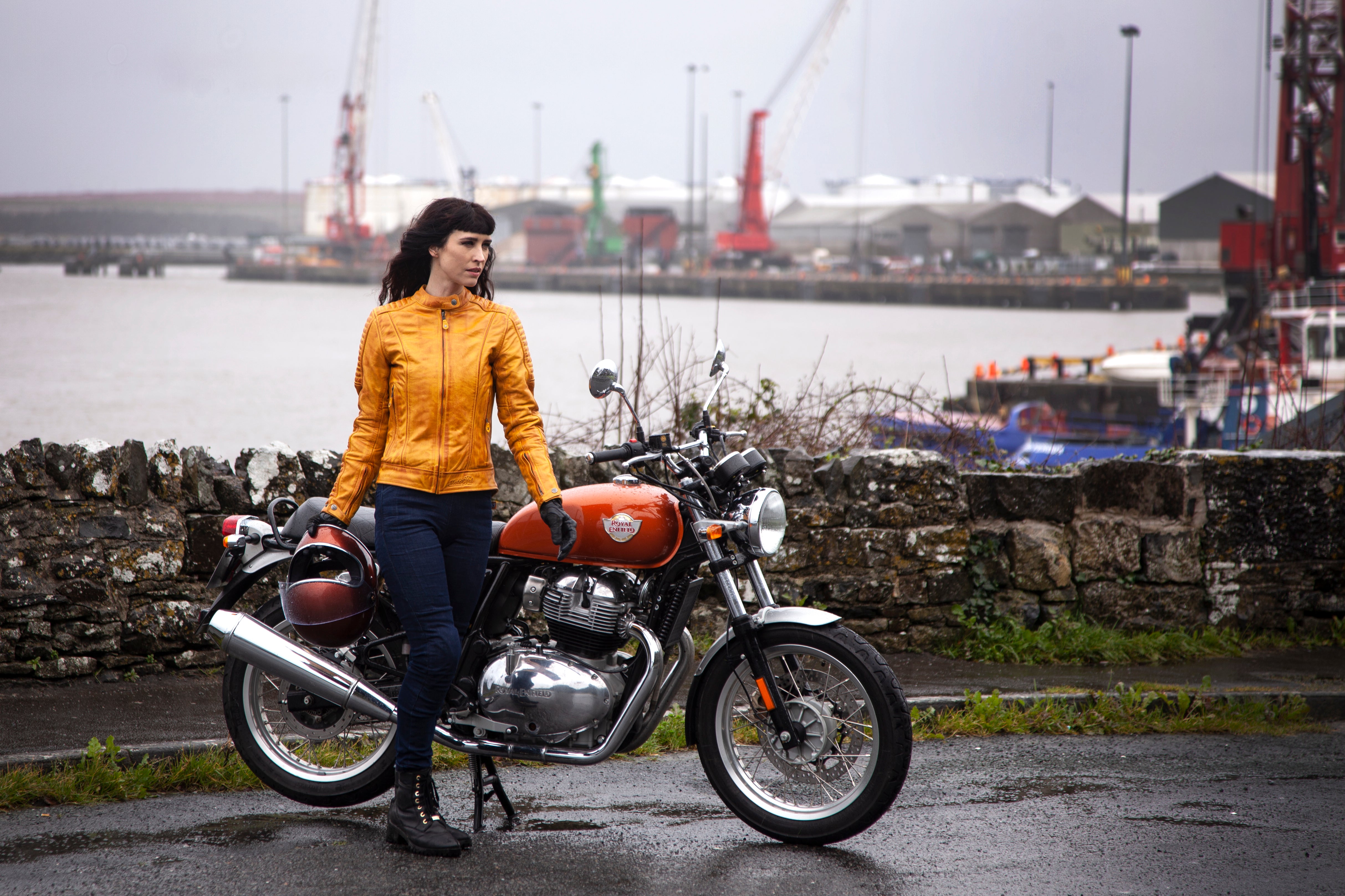 A woman with her motorcycle wearing yellow Valerie motorcycle leather jacket from MotoGirl