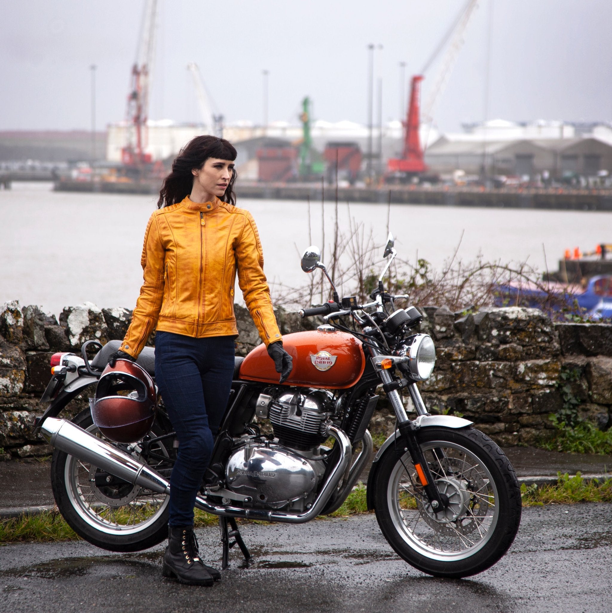 A woman with her motorcycle wearing yellow Valerie motorcycle leather jacket from MotoGirl