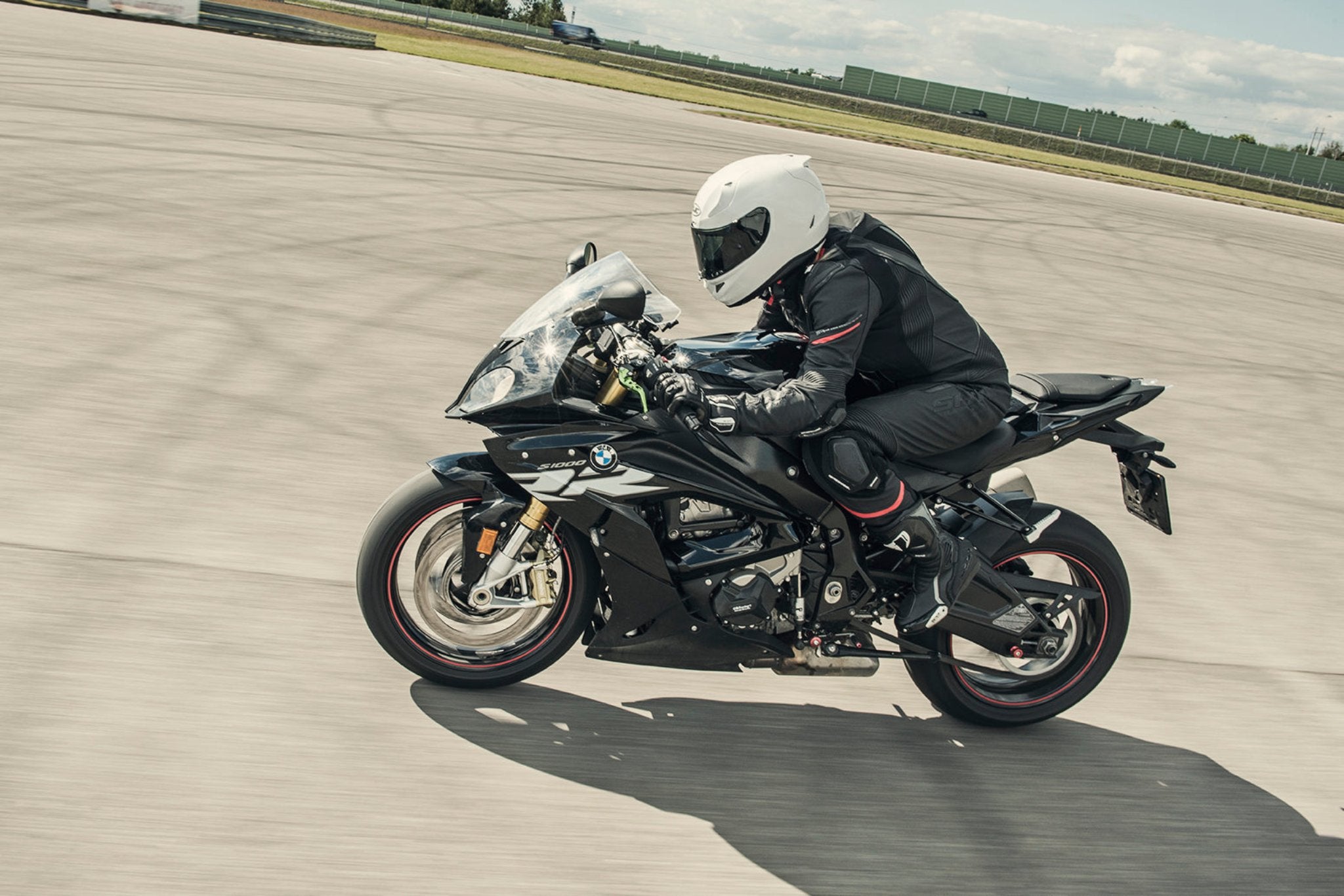 A woman racing on a motorcycle wearinh Black and red women&#39;s motorcycle racing suit from Shima