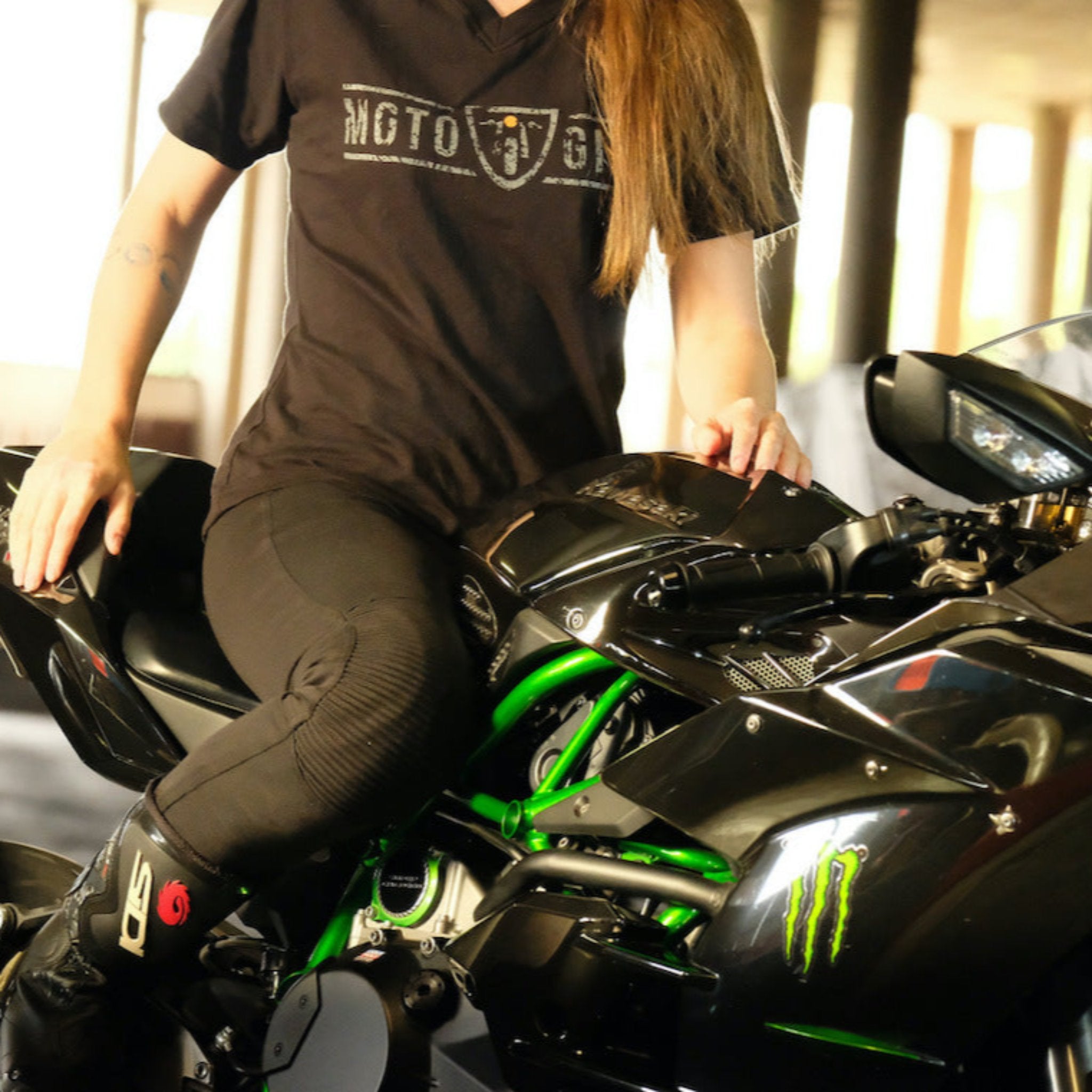 A woman on a motorcycle wearing motorcycle leggings and MotoGirl Tshirt