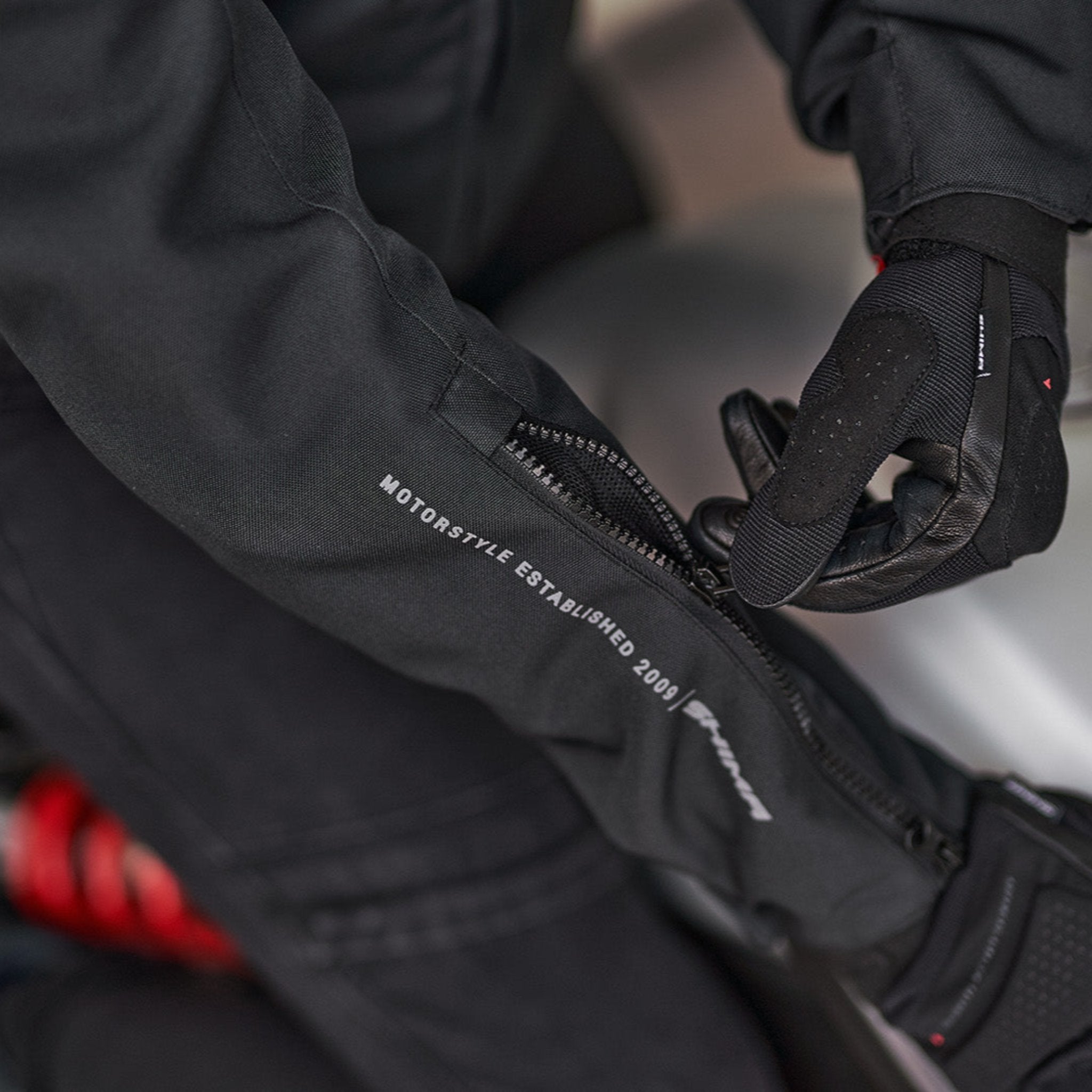 Woman&#39;s hands zipping the sleeve of the motorcycle jacket