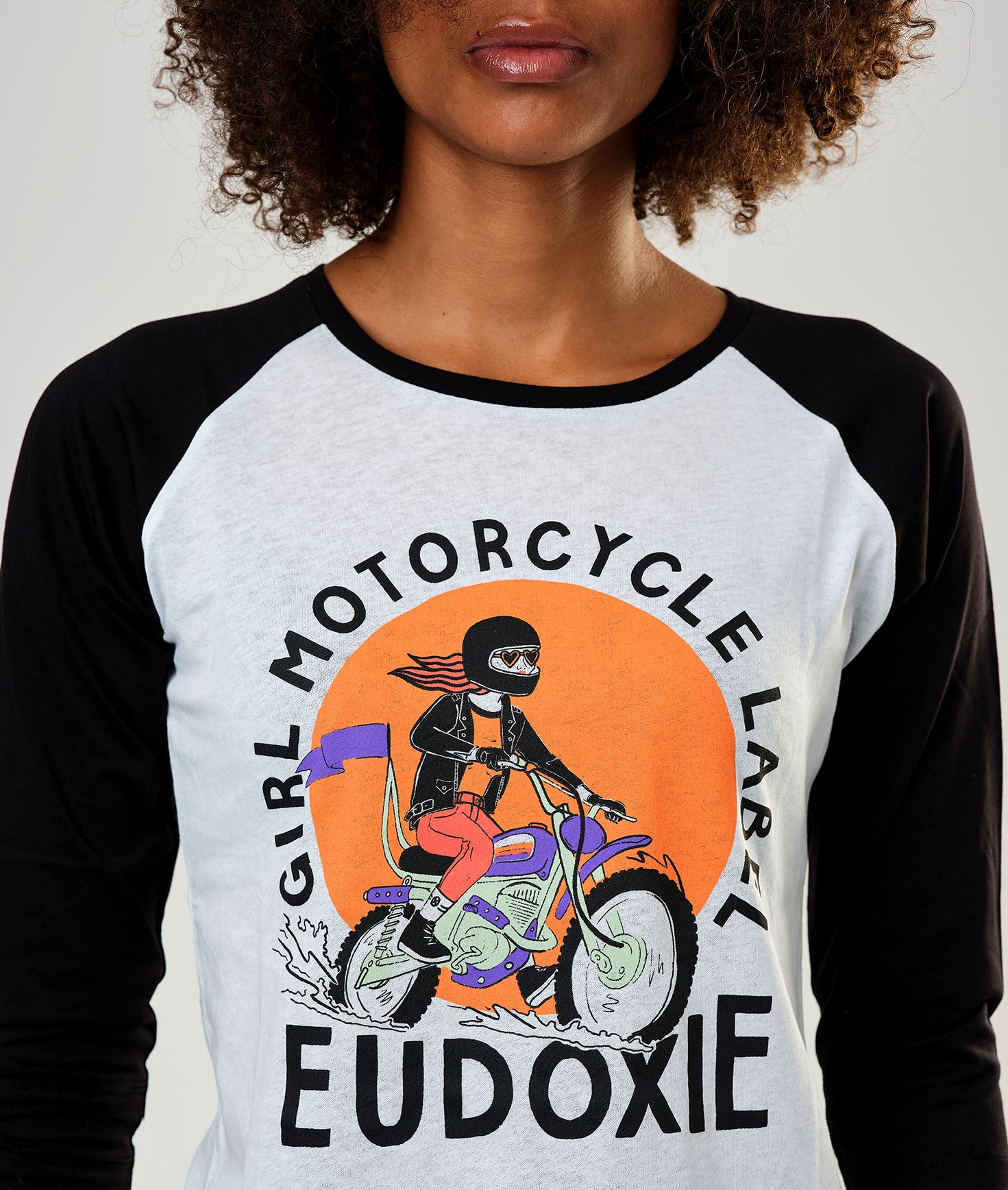 A young woman wearing black &amp; white baseball motorcycle t-shirt with Girl motorcycle label motive from Eudoxie 